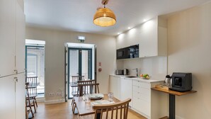 Una cocina moderna con microondas, cafetera y un pequeño comedor con sillas y mesa de madera.
