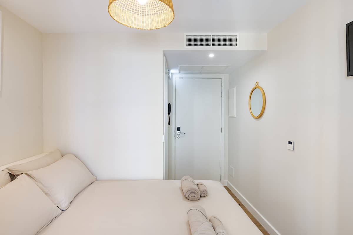 Ein Hotelzimmer mit einem Bett, einer Tür, einer Leuchte und einem an der Wand montierten Lichtschalter.