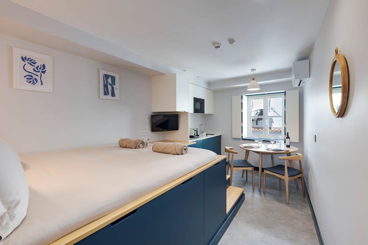 Ein modernes Hotelzimmer mit Bett, einer kleinen Essecke, einem Fernseher und Kunstwerken an den Wänden.