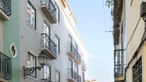 Una estrecha calle adoquinada flanqueada por edificios de varios pisos con balcones y ventanas.