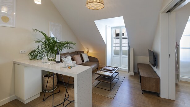 Un loft moderno con comedor, sofá, televisor y un amplio ventanal.