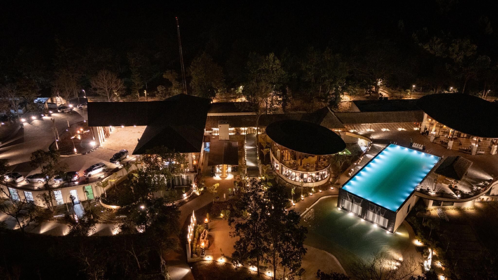 A resort with a swimming pool, multiple buildings, and a parking area.