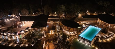 A resort with a swimming pool, multiple buildings, and a parking area.