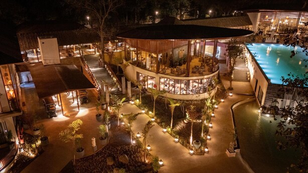 Un resort de varios niveles con piscina, zona de estar al aire libre y un espacio central bien iluminado.