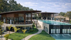 Un resort moderno con una gran piscina, un espacio exterior cubierto y un césped bien cuidado.