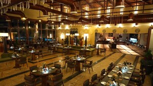 Un amplio vestíbulo de hotel con varias zonas de restauración, grandes ventanales y un bar.