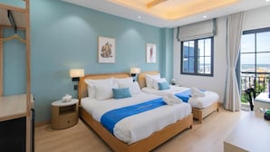 A hotel room with two beds, a balcony with a view, and a ceiling fan. - Maison Villa By The Sea (Ho Chi Minh City)