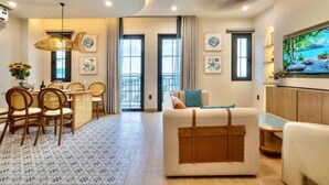 A spacious living room with a dining area, featuring a large sofa, a dining table with chairs, and a ceiling fan. - Maison Villa By The Sea (Ho Chi Minh City)