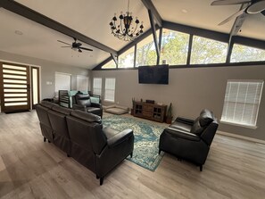 A spacious living room with a large sectional sofa, a fireplace, and a ceiling fan.