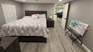 Un dormitorio con cama, mesita de noche, lámpara y un cuadro en la pared.