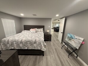 Una camera da letto con un letto, un comodino, una lampada e un quadro appeso al muro.
