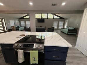 A modern kitchen with a large island, built-in oven, and a dining area with a sofa and chairs.
