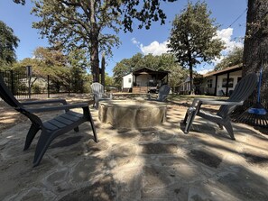 Un'area esterna con sedute tipo Adirondack, un braciere in pietra e vista su un edificio sullo sfondo.