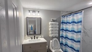 Un baño con inodoro, lavabo, espejo y toallero.