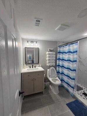 Un bagno con WC, lavandino, specchio e portasciugamani.
