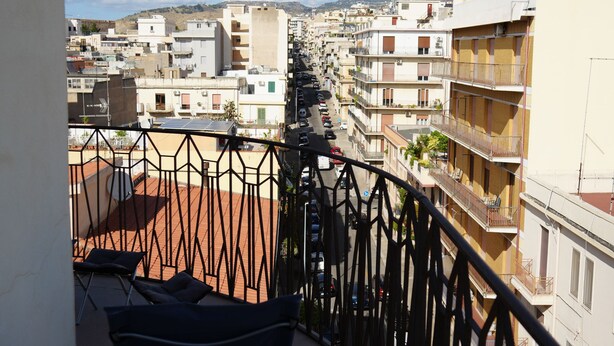 A balcony with a metal railing overlooking a residential area with multiple buildings. - La Regina del Sole (Reggio Calabria)
