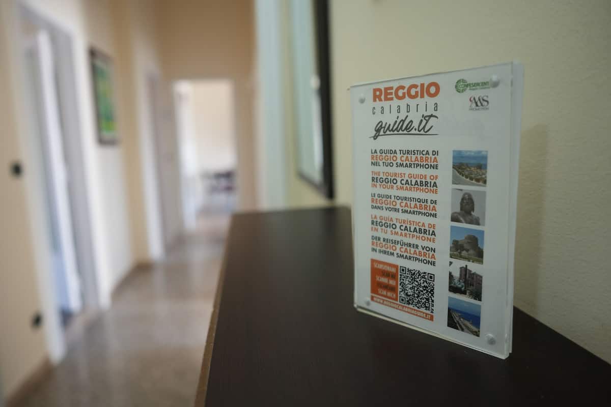 A sign with the text "REGGIO Calabria guide.it" and QR code.