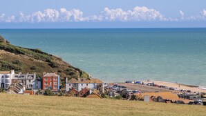 A coastal town with buildings along the shore, a parking area, and a view of the sea. - Thistle Villa (Hastings)