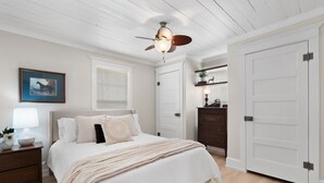 A bedroom with a bed, nightstand, dresser, and a ceiling fan.