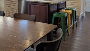A kitchen with light-colored cabinets, a central island, and a dining area with a wooden table and chairs. - Beach House in Venice Florida, welcome to paradise. (Venice)