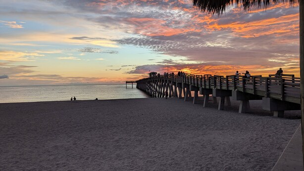 A beach with a wooden pier extending into the sea, featuring a viewing platform with people. - Beach House in Venice Florida, welcome to paradise. (Venice)