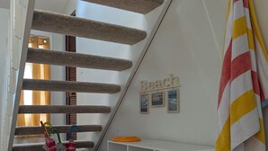 A staircase with a checkered carpet, a basket with umbrellas, a towel rack, and a wall with a 'Beach' sign. - Beach House in Venice Florida, welcome to paradise. (Venice)