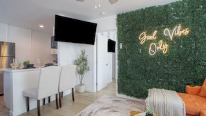 A modern living room with a green wall, a sofa, a coffee table, and a TV mounted on the wall. - Tiny but Mighty Home - 5 min to ASU & Mill Ave (Tempe)