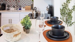 A kitchen with a checkered backsplash, a kettle, a wine glass, and black bowls on orange plates. - Tiny but Mighty Home - 5 min to ASU & Mill Ave (Tempe)
