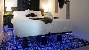 A modern bedroom with a large bed, bedside lamps, a decorative mirror, and a patterned rug. - Tiny but Mighty Home - 5 min to ASU & Mill Ave (Tempe)