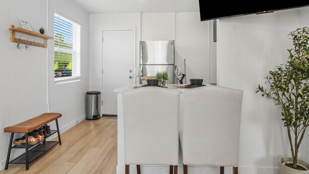 A modern kitchen with white cabinetry, a built-in oven, and a dining area with a bench and table. - Tiny but Mighty Home - 5 min to ASU & Mill Ave (Tempe)