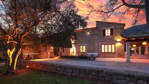 A stone building with multiple windows and a covered outdoor seating area. - H2947 Finca Papa near Pollenca for 12 persons near Pollenca (Pollenca)