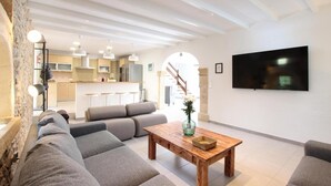 A modern living room with a sofa, a wooden coffee table, and a TV mounted on the wall. - H2947 Finca Papa near Pollenca for 12 persons near Pollenca (Pollenca)