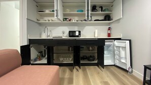 A compact kitchenette with a microwave, sink, and storage cabinets. - Guest Suite (Winnipeg)
