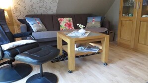 A living room with a sofa, a wooden coffee table, a black leather chair, and a cabinet. - NEW! Vacation apartment Sonnenschein OG (Neuschoo)