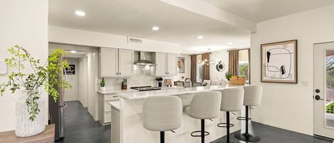 A modern kitchen with a central island, bar stools, and a view of the outdoors.