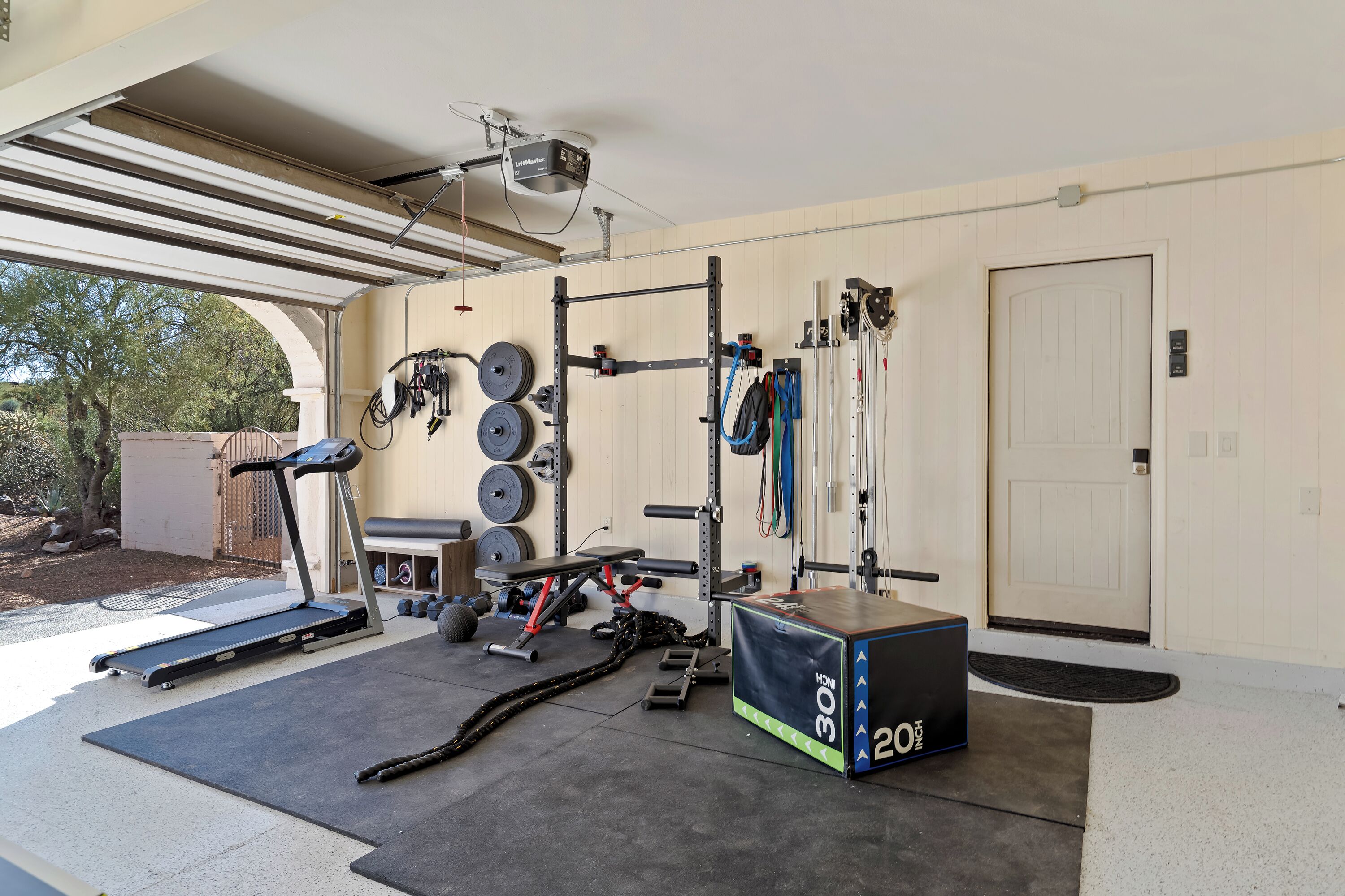 Een huisgym met een loopband, een gewichtbank en diverse fitnessapparaten.