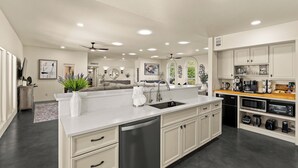 A modern kitchen with a central island, built-in appliances, and a dining area with a wooden table and chairs. - Luxury 5BR Foothills Home Heated Pool & Spa, Gym, Mountain Views Sleeps 16 (Tucson)