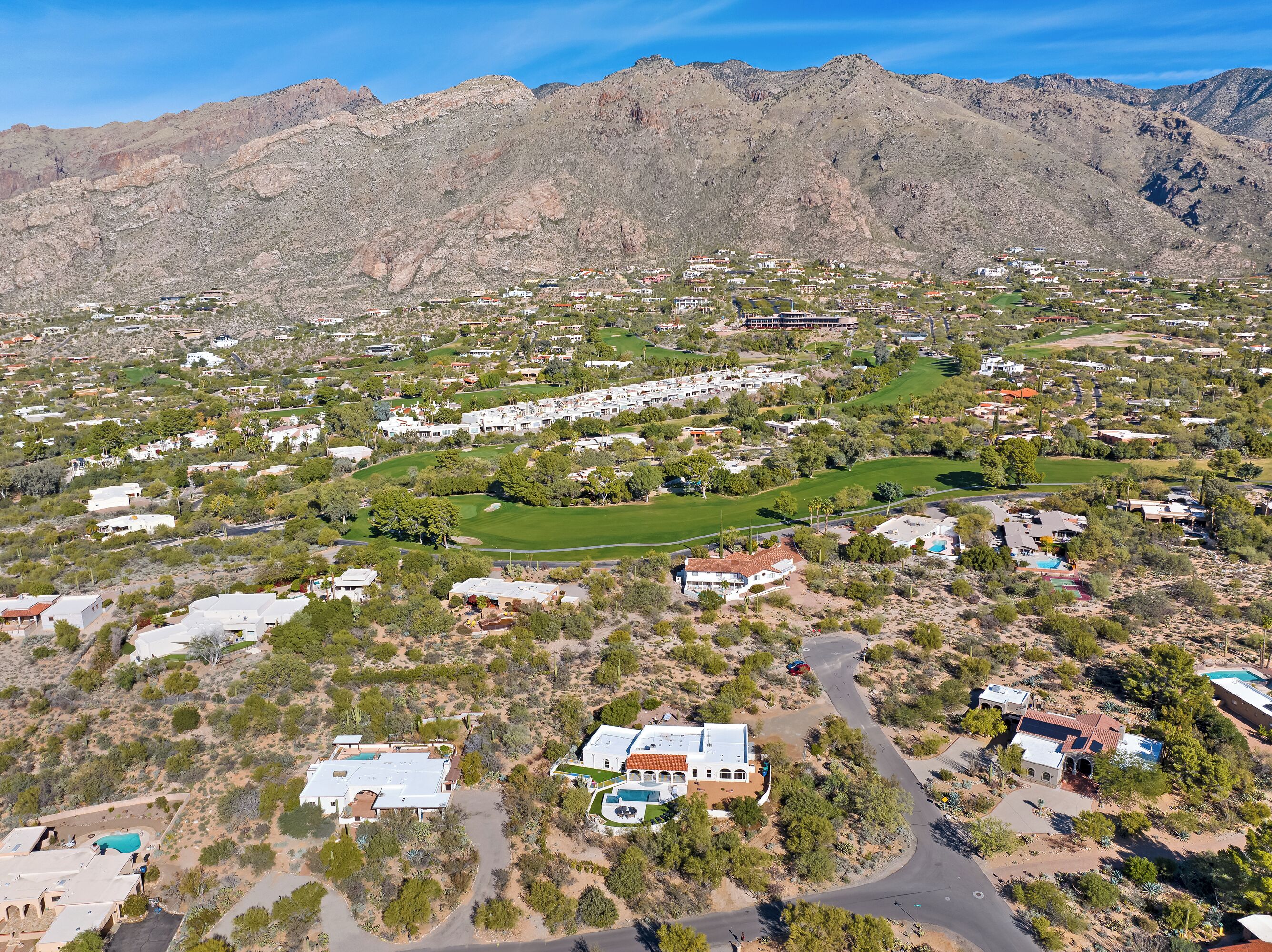 An aerial view of a residential area with houses, green spaces, and a golf course.