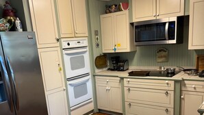 Eine Küche mit weißen Schränken, einem Edelstahl-Kühlschrank, einer Mikrowelle und einer Kaffeemaschine.