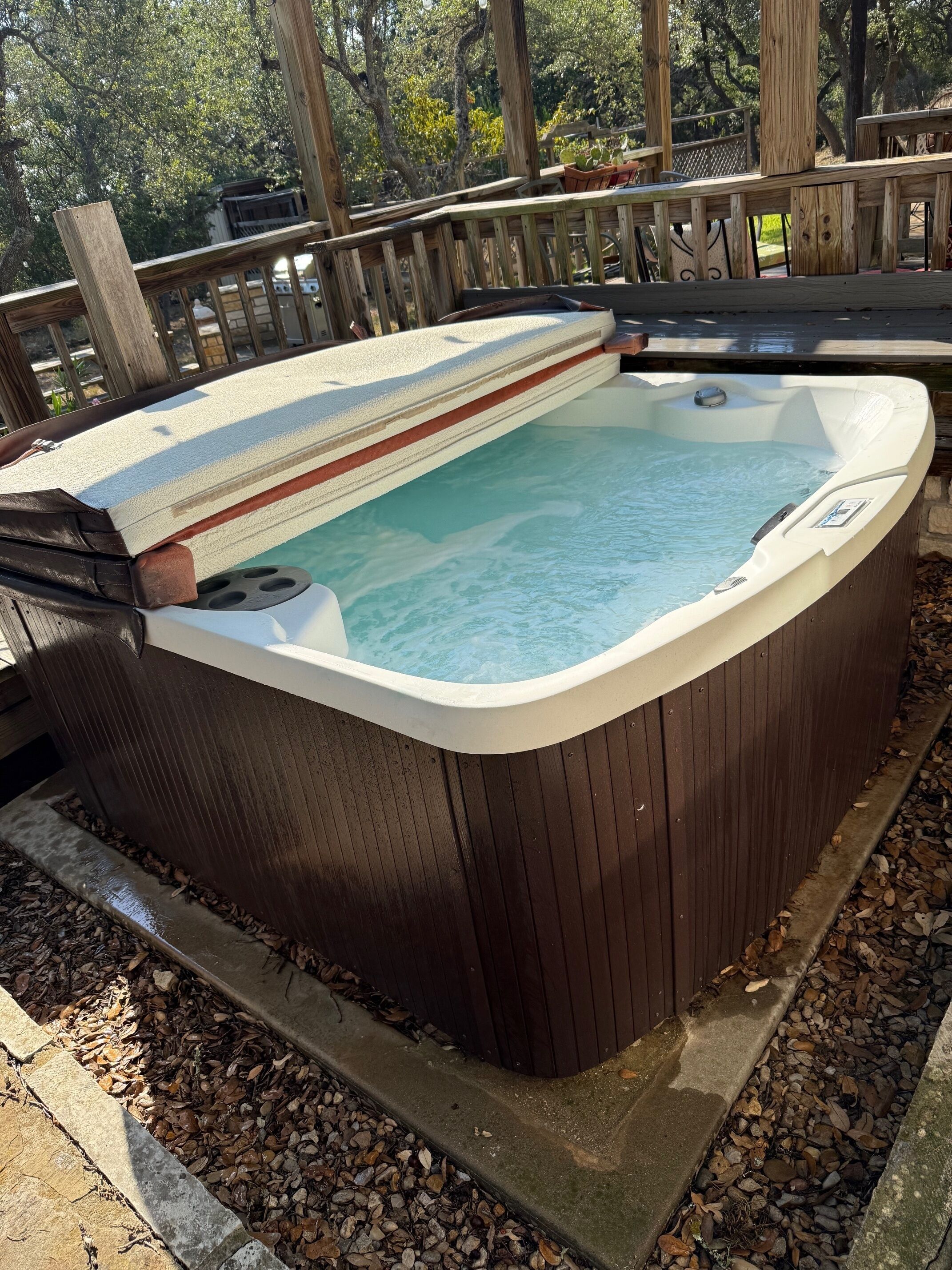 A hot tub with a wooden deck and a stone border.