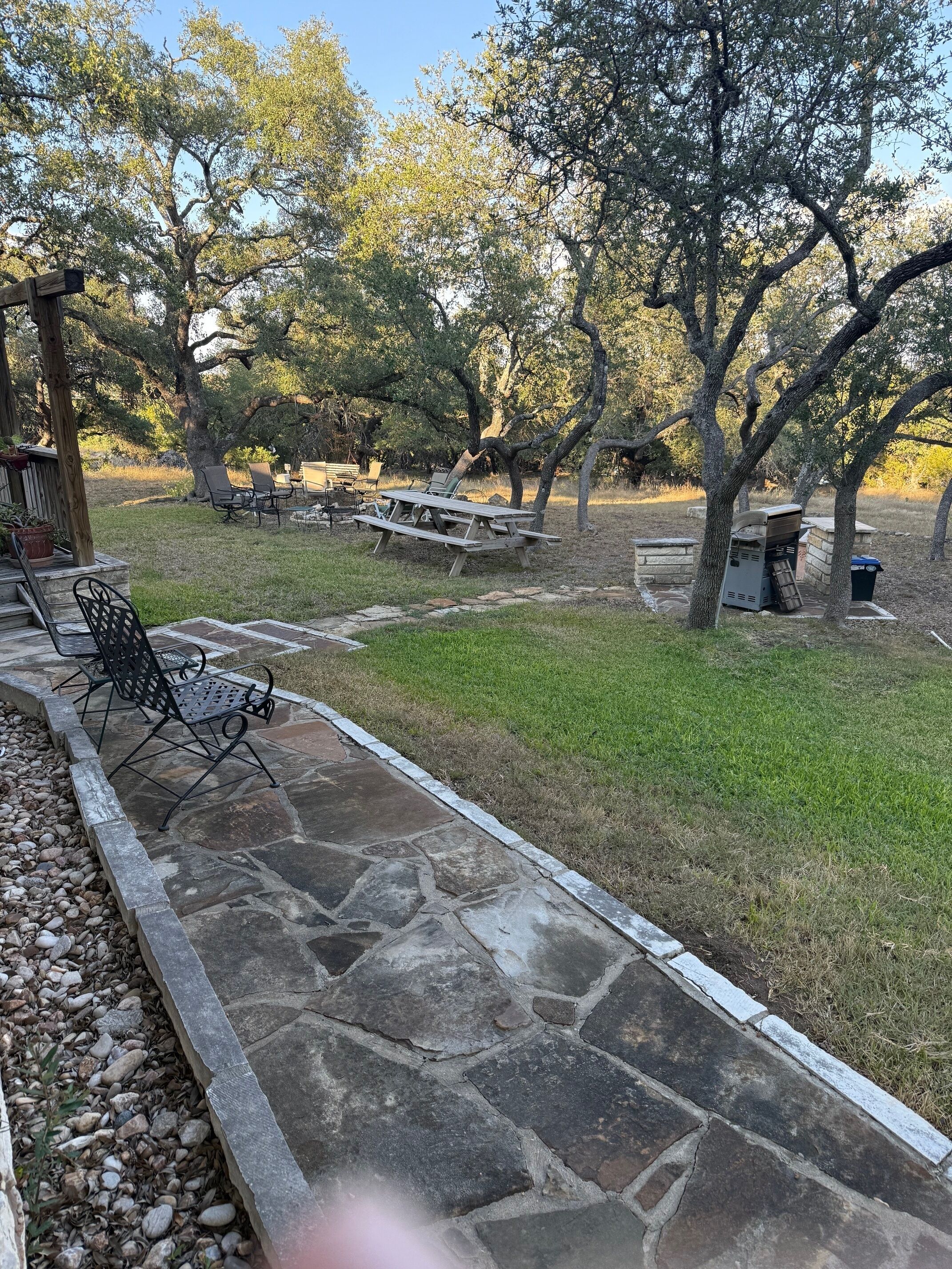 A patio area with stone flooring, outdoor furniture, and a grassy lawn.