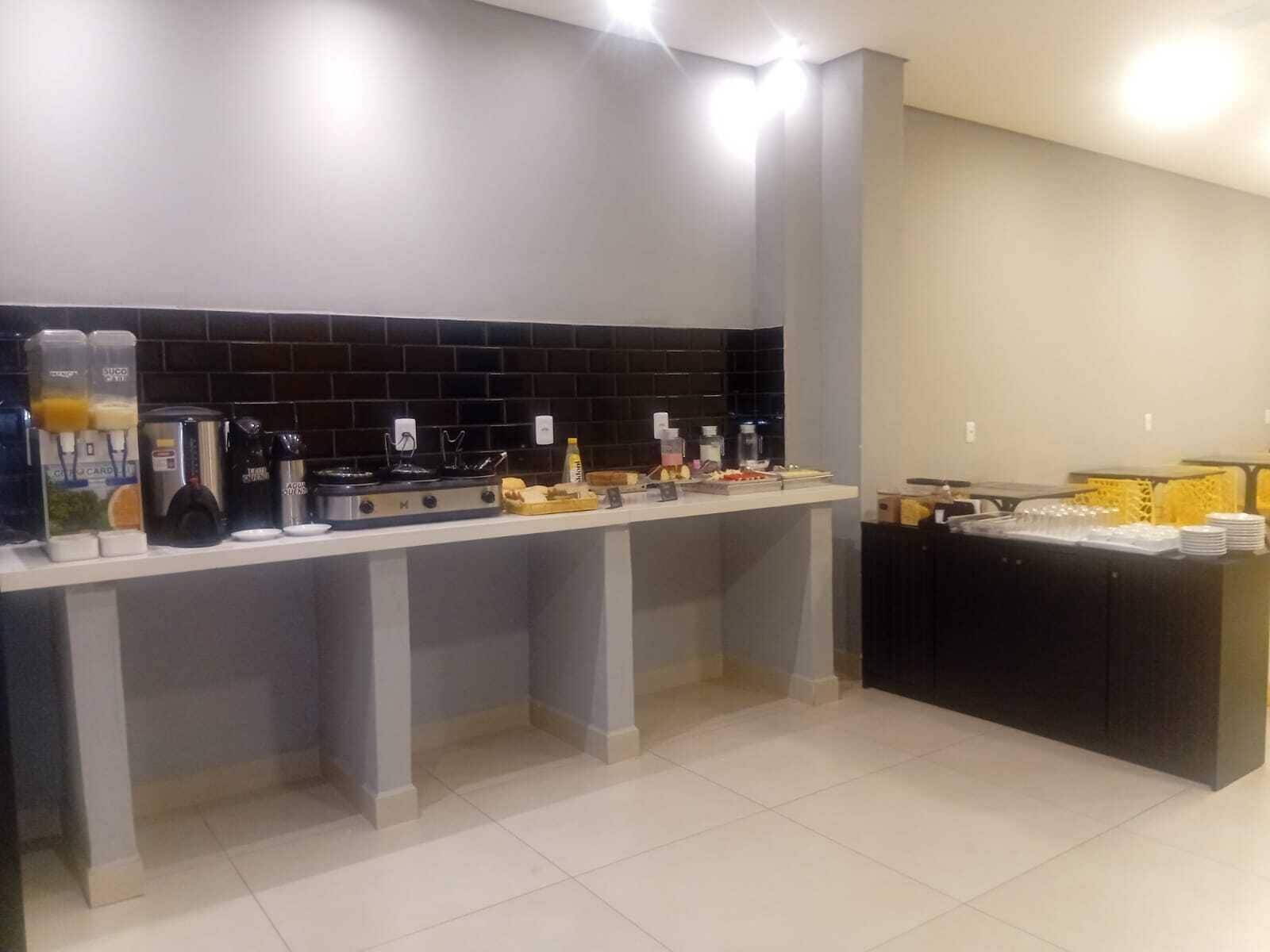 A modern kitchen with a black tiled backsplash, a coffee machine, and a buffet area with stacked plates and glasses.