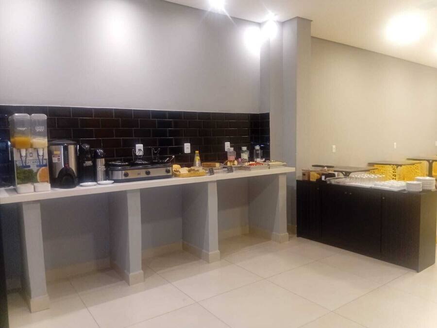 Une cuisine moderne avec un mur recouvert de carreaux noirs, une machine à café et un espace buffet où sont disposées des assiettes et des verres empilés.