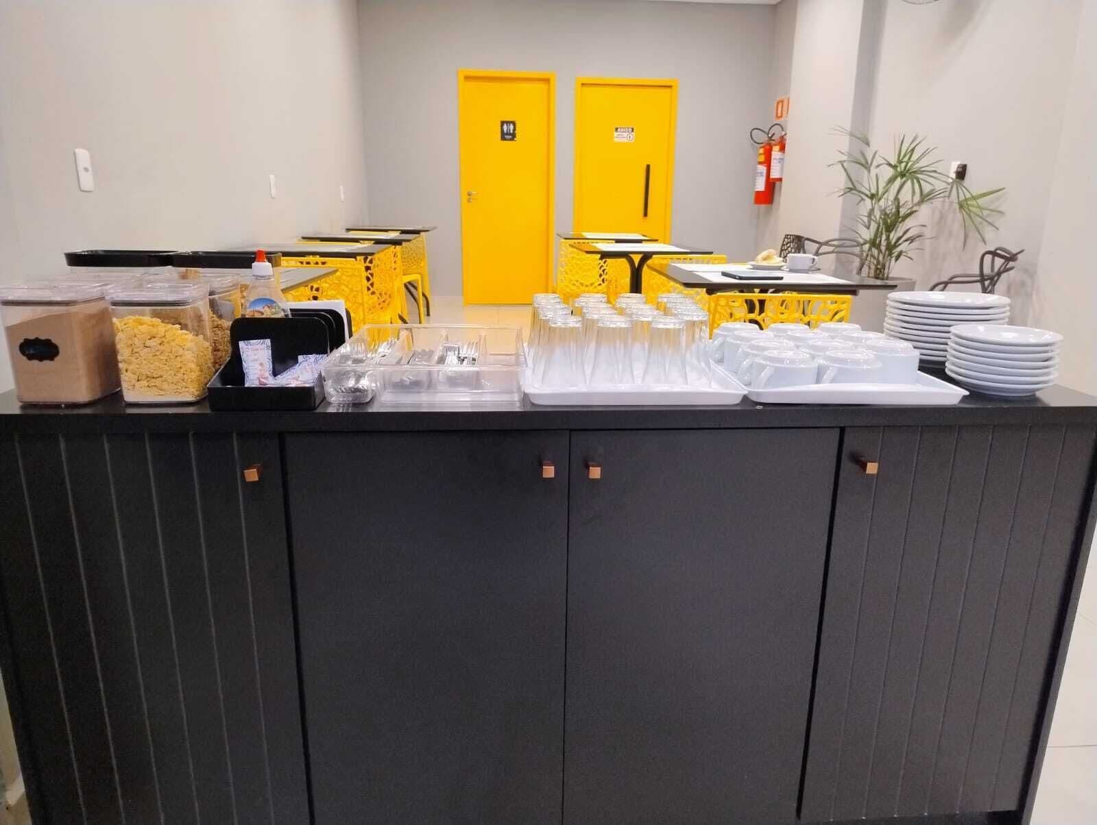 A buffet setup with various food containers, a yellow door in the background, and a fire extinguisher on the wall.
