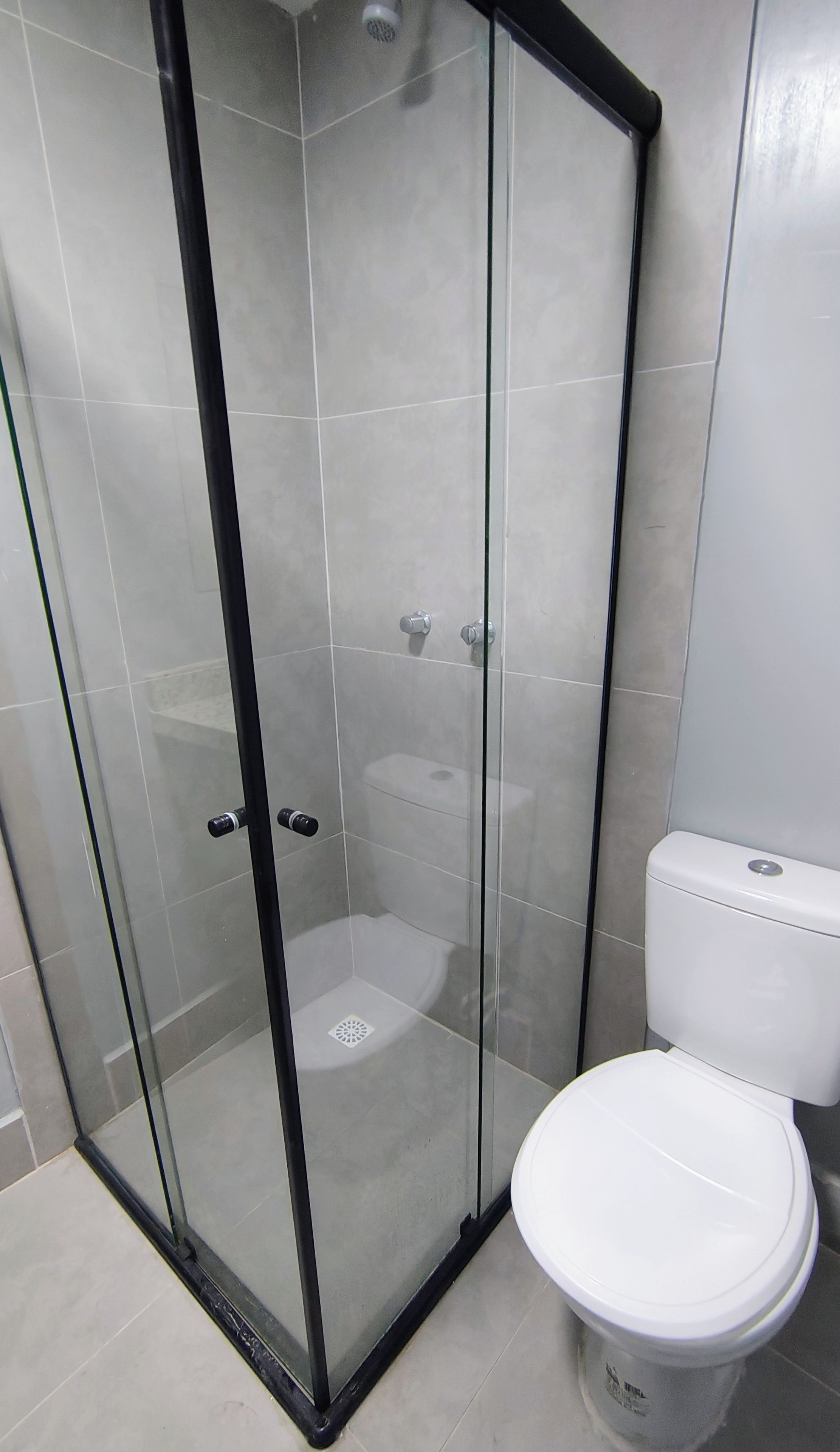 A bathroom with a glass-enclosed shower, a white toilet, and tiled walls.