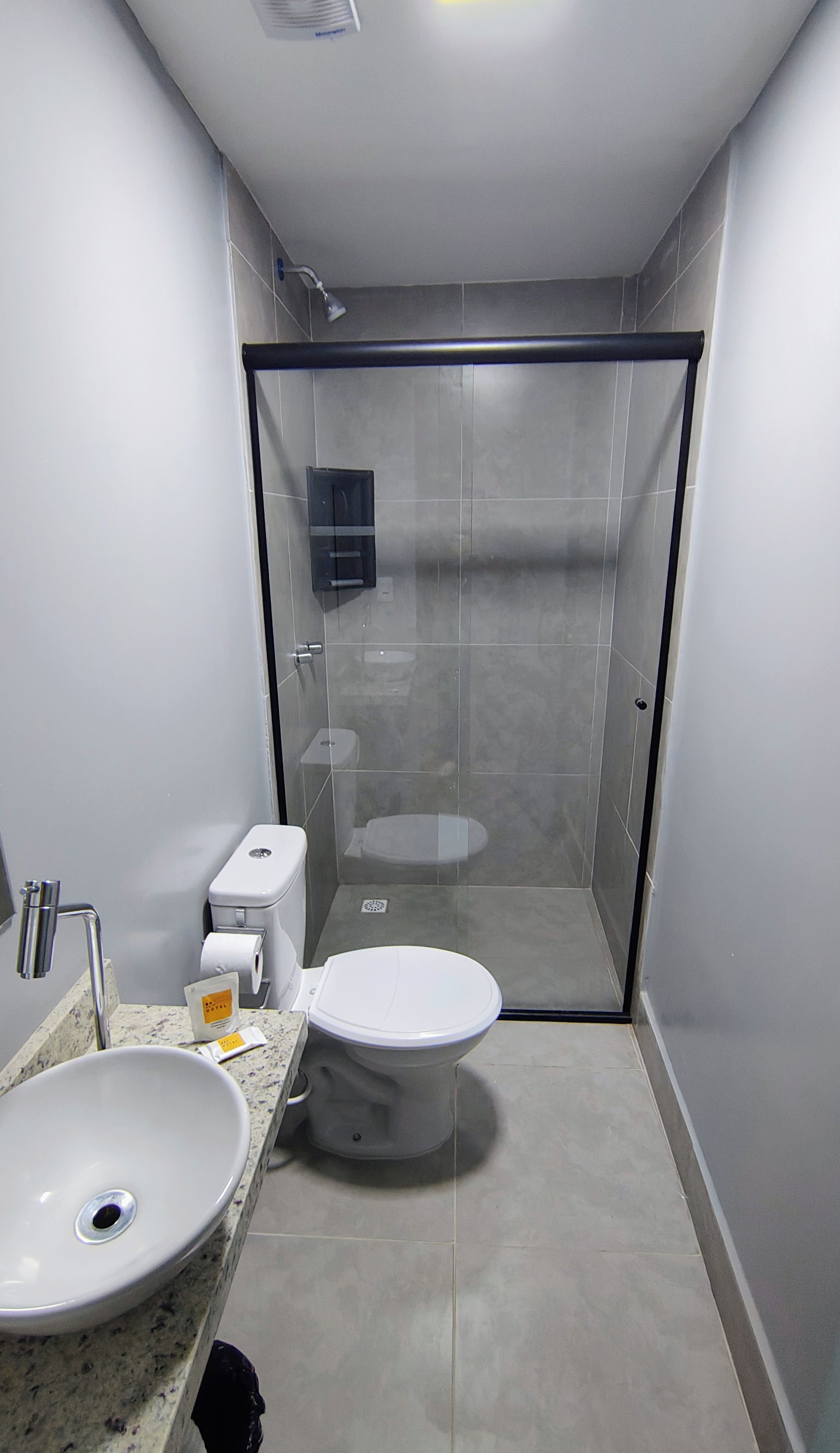 Une salle de bain moderne avec une douche à parois de verre, un lavabo blanc et des toilettes.