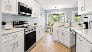 A modern kitchen with white cabinetry, stainless steel appliances, and a large window providing natural light. - NEW 5-Bed house in Jacksonville 5m from Beach, UNI, Bars, (Jacksonville)