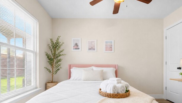 A bedroom with a bed, a ceiling fan, a window with blinds, a potted plant, and wall art. - NEW 5-Bed house in Jacksonville 5m from Beach, UNI, Bars, (Jacksonville)