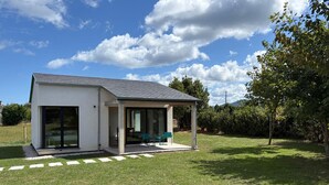 Una casa moderna de un piso con un porche cubierto, grandes puertas correderas de vidrio y un jardín bien cuidado.