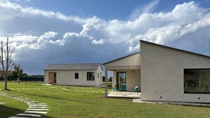Una casa moderna con un porche cubierto y una edificación separada.